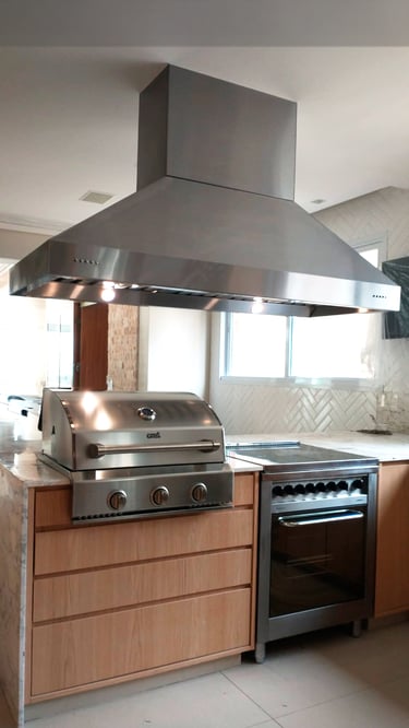 Ilha de cozinha moderna com coifa preta instalada acima de um cooktop a gás embutido.