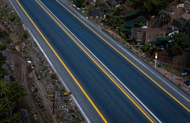 An aerial drone view of a completed highway segment in Mexico, showcasing perfect asphalt and professional markings in Steel Blue and safety yellow tones.