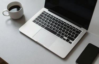 A high-angle shot of a minimalist workstation with a sleek laptop and a cup of coffee on a light grey surface, representing clean design and focus. North American setting.