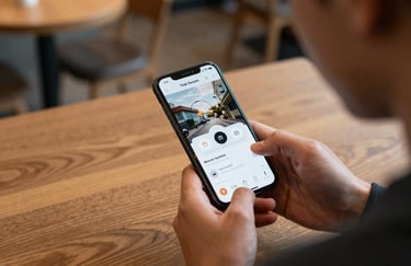 An over-the-shoulder shot of a person using a beautifully designed app on a smartphone while sitting in a contemporary North American coffee shop.
