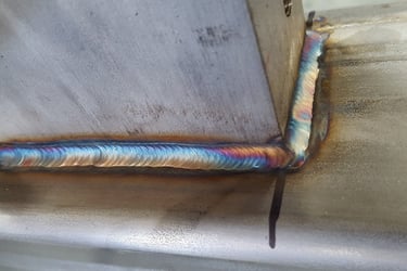 Close-up of a high-quality TIG weld on stainless steel with vibrant heat tint coloration.