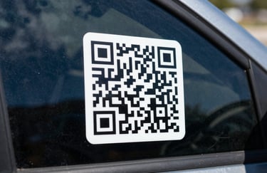 Macro photography of a sleek QR code sticker on a vehicle's side window, reflecting a blue North American sky.