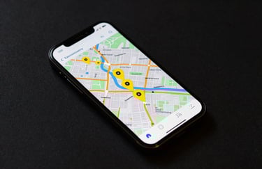 Top-down view of a smartphone on a dark surface, showing a vibrant map app with several yellow location pins in a US city.