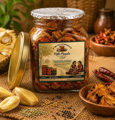 A glass jar of homemade Mitti Masala Kathal ka Achar spicy jackfruit pickle surrounded by Indian spices.