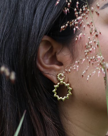 Mujer de perfil que muestra un arete en oro laminado