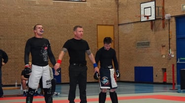 Level 4 sports therapist TJay Harvey having his hand raised at a martial arts competition.