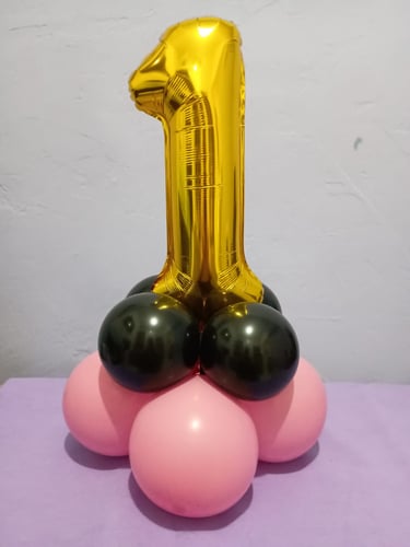 Gold number one foil balloon on a black and pink latex balloon base for a first birthday party.