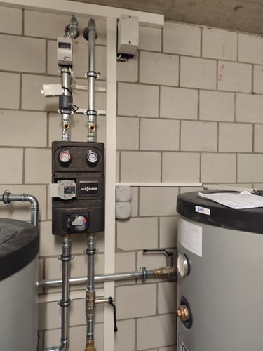 Professional Viessmann boiler heating system installation with insulated pipes and storage tanks.