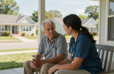 A caregiver and a senior sitting on a porch in a North American suburban neighborhood, sharing a quiet moment during a sunny afternoon.