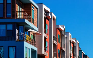 Modern garden-style condo building with colorful facades and balconies against a clear blue sky.