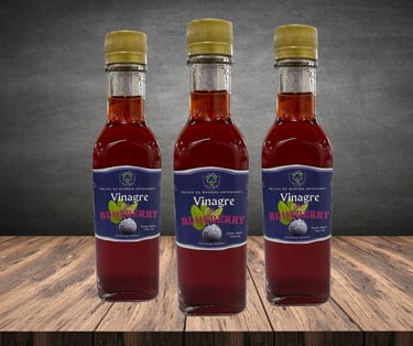 Tres botellas de vidrio de vinagre de arándanos artesanal sobre una mesa de madera rústica con fondo