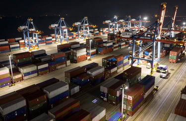 Aerial view of a busy cargo port at night with light trails. International / Global connectivity. Sophisticated and authoritative tone. Crisp off-white highlights.