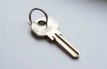 A macro photography shot of a clean, metallic digital key resting on a mist white surface. The lighting is soft and focuses on the texture of the metal, symbolizing security and encrypted access.