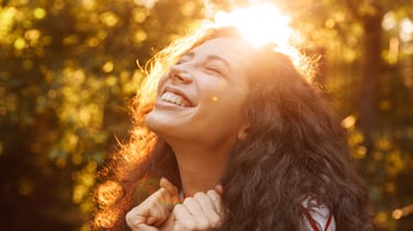 Mulher morena sorrindo ao por do sol