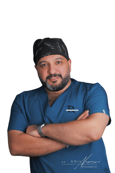 Portrait of Dr. Adil Nasrawi, a professional orthodontist in blue medical scrubs and a surgical cap.