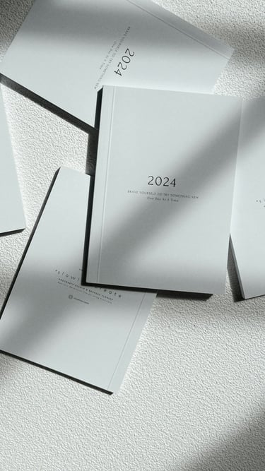 Flat lay of minimalist 2024 planners and journals with elegant typography on a textured surface.