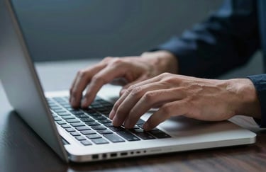 A focused shot of hands typing on a laptop with a soft steel blue backlight, suggesting a diligent and expert work environment.
