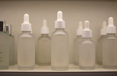 A detailed photograph of several premium, frosted glass skincare bottles arranged on a shelf. The lighting is soft neutral beige with sharp, clean focus. No branding, only minimalist design in a North American / US setting.