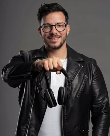 DJ Boss in Portugal souriant avec une veste en cuir, tenant son casque audio professionnel prêt pour mixer en club.