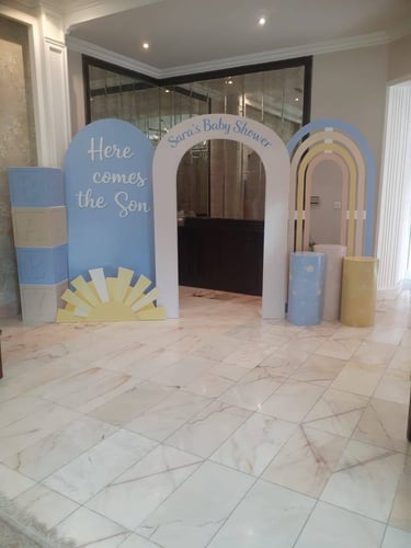 ديكور حفل استقبال مولود من الفلين يشمل أقواس ملونة ومكعبات بعبارات ترحيبية