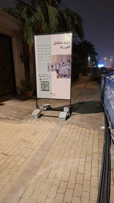 لوحة إعلانية لمشروع عقاري مطبوعة بجودة عالية ومثبتة على حامل حديدي في طريق سكني