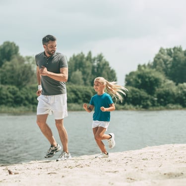 Father and daughter jogging together along a riverside path