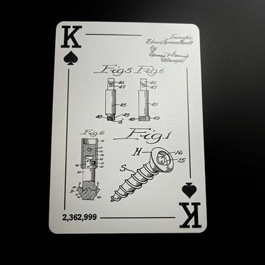 A king of clubs is shown face up on a black surface. Engineering drawings of a screw are centered.