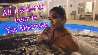 MsMadyson in a chocolate swimsuit in a hot tube at night holding a pink cup that says Yes Mistress