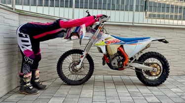 Yogalehrerin Anja am Motorrad in einer Vorbeuge mit langem Rücken zur Entlastung in der Pause