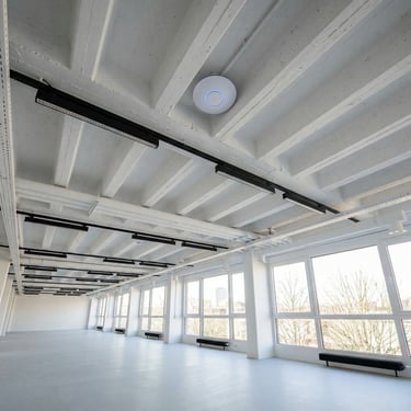 Modern white industrial office space featuring a ceiling-mounted WiFi access point and track lighting.