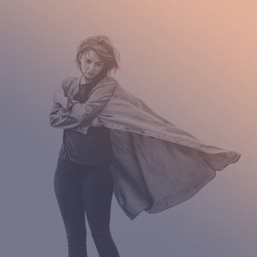 Moody portrait of a person standing with eyes closed, arms crossed, and a long shirt flowing in the