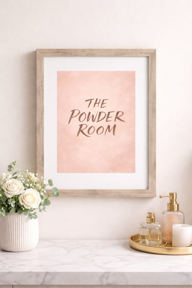 Framed pink powder room wall art on a marble counter with white roses and gold bathroom accessories.