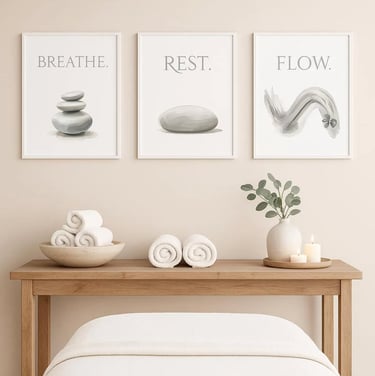 Zen spa decor with framed wall art featuring stones, stacked towels, and a lit candle on a wooden table.