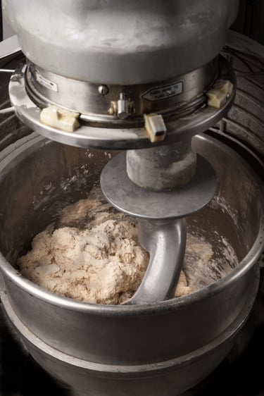 Commercial mixer working pizza dough.