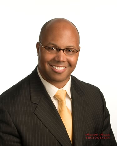 Headshot for a political office candidate. White background, man in dark suit and yellow tie. #busiiness photography,  