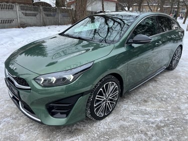 Dark green Kia ProCeed shooting brake parked on a snowy road with stylish alloy wheels.