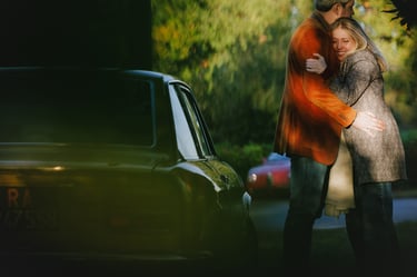 Lui e lei abbracciati in un paesaggio autunnale di fianco ad una macchina d'epoca Fiat