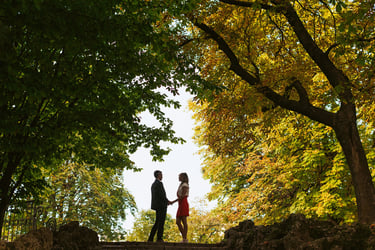 Nel parco di Porta Venezia a Milano, una coppia si tiene per mano circondata da alberi maestosi