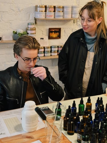 A man smells a sample at a custom perfume workshop with essential oil bottles on the table.