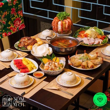 Traditional Vietnamese family dinner spread with seafood hotpot, grilled chicken, shrimp, and fresh fruit.