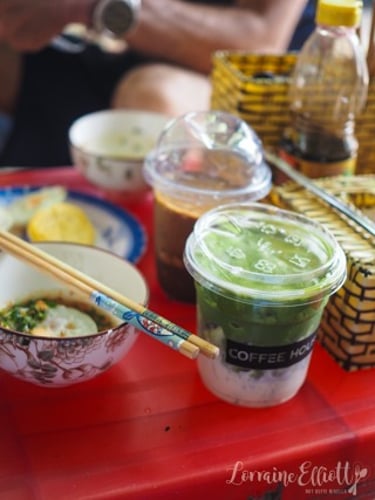 Iced matcha green tea latte and Vietnamese coffee on a red table with breakfast bowls and chopsticks.