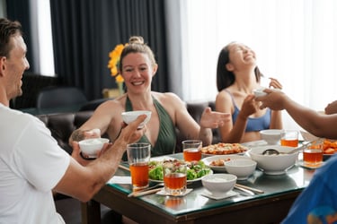 Happy friends enjoying a healthy meal together with rice and tea at a dining table.