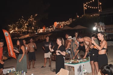 A group of friends enjoys a beach party at night with BBQ at Cam Ranh Surf Camp