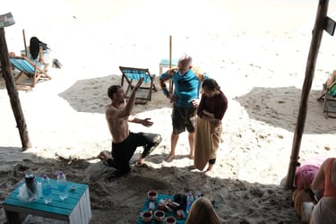 Surfing instructor demonstrating technique on a sandy beach to students at a coastal surf school.
