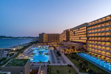 Luxury beach resort at dusk featuring illuminated swimming pools and modern oceanfront architecture.
