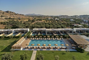 Aerial view of a luxury Rhodes resort featuring a large swimming pool, sun loungers, and private villa suites.