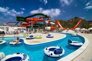 A sunny water park with a lazy river, inflatable tubes, and colorful twisting water slides.