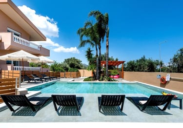 Luxury villa rental featuring a private swimming pool with sun loungers and palm trees.