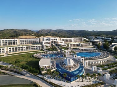 Aerial view of a luxury coastal resort featuring blue swimming pools and modern architecture.