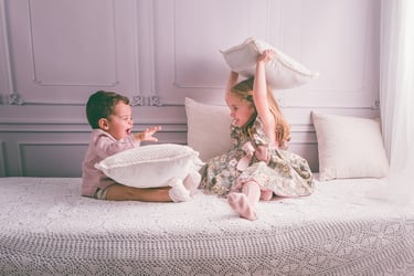 Sesión de familia en estudio, donde dos hermanos juegan divertidos, realizado en Almendralejo por Amélie Art.